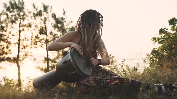 Beautiful Young Hippie Woman with Dreadlocks Playing on Djembe