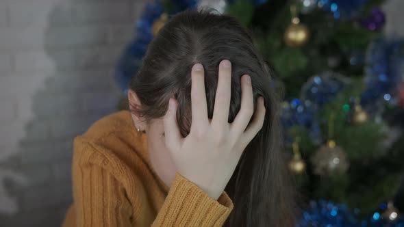 Tired girl by decorated tree.