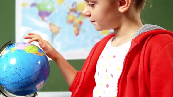 Schoolgirl looking at globe in classroom at school