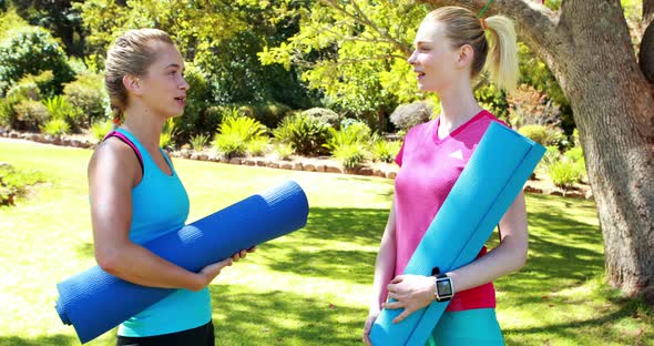 Beautiful women holding exercise mat and interacting with each other