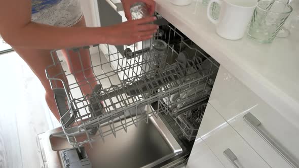 Woman Putting Glass in the Dishwasher at Home