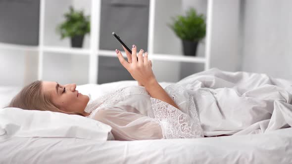 Adorable Lazy Female Relaxing on Soft Pillow Scrolling Social Networks