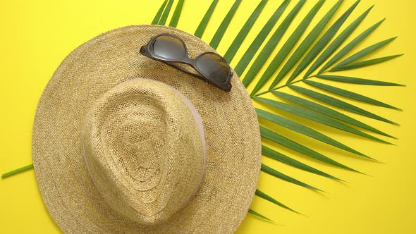 Straw Hat Green Palm Leaf and Sunglasses on Yellow Backdrop