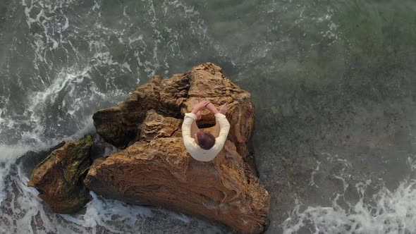 A Man Sits on a Stone and Looks at the Sea