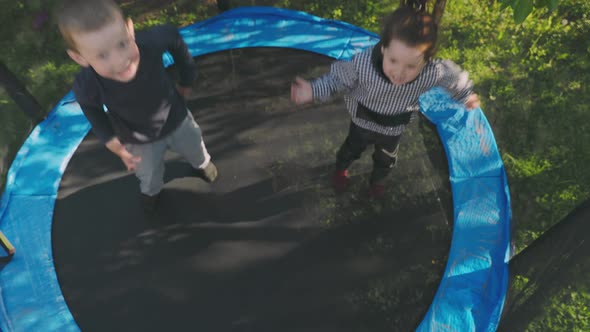 Two Children Have Fun Jumping on a Trampoline