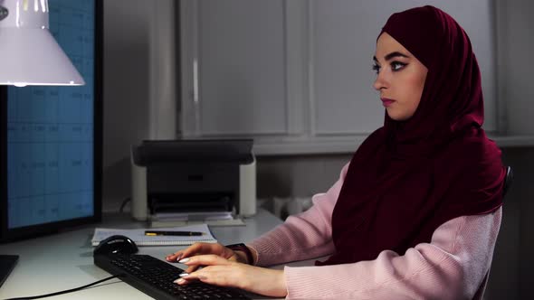 Female Manager in Hijab Works at Office Typing on Keyboard Stops and Smiling