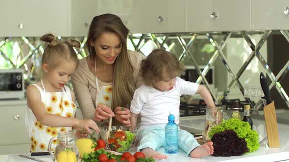 Woman With Kids Cooking Vegetables Salad At Kitchen