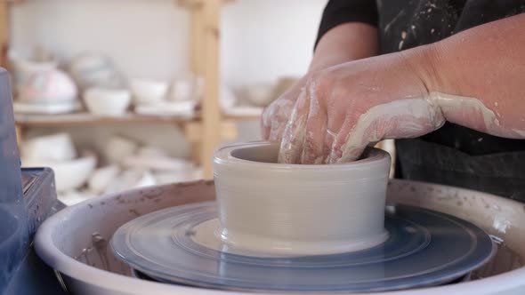 Crop ceramist sculpturing with clay on wheel