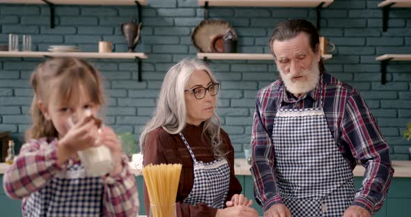 Senior Grandparents Couple with Dgranddaughter Cooking in Kitchen