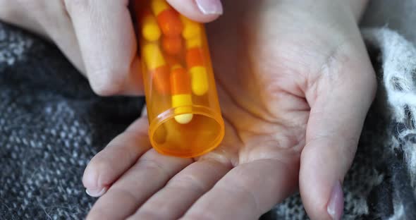 Person Pours Pills Out of Bottle Closeup