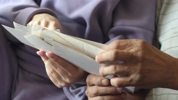 Father shows old family photo concept to adult daughter. Close-up of the hands of a pensioner and da