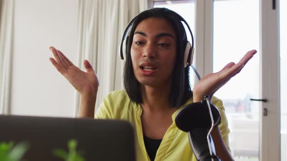 Mixed race gender fluid person recording a podcast using laptop at home