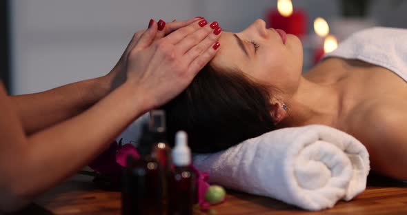 The Masseur Gently Strokes the Forehead of a Young Woman