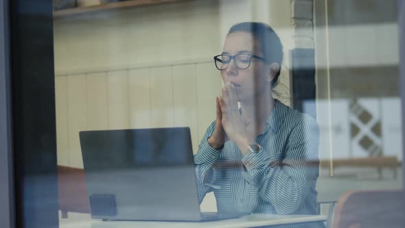 Cafe Window and a Lady Operating a Laptop Is Filmed Through It