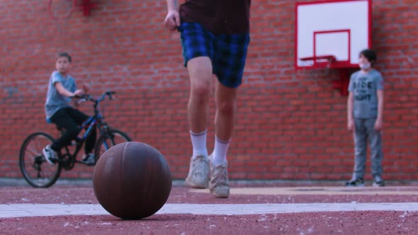 Young Man on the Basketball Playground Running After Ball