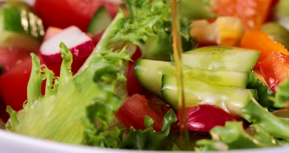 Olive Oil Is Poured on a Vegetable Salad in a Plate