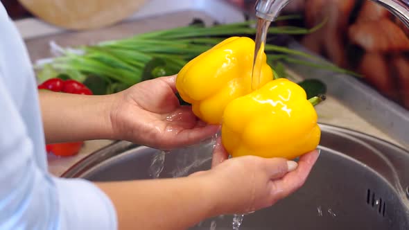 Woman Washing Yellow Pepper in Kitchen