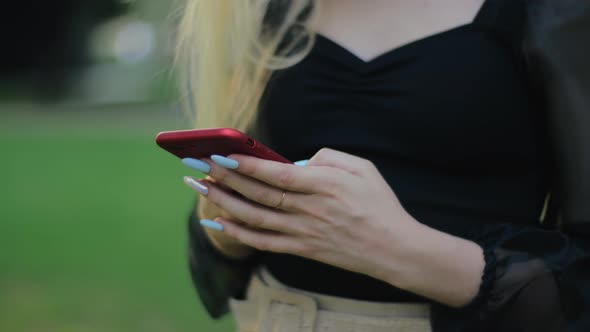 Teen Girl in Black Stylish Dress and with Manicure Types Text Message on Her Smartphone