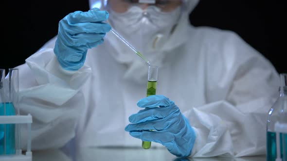 Scientist in Protective Suit Taking Liquid Sample From Test Tube With Radiation