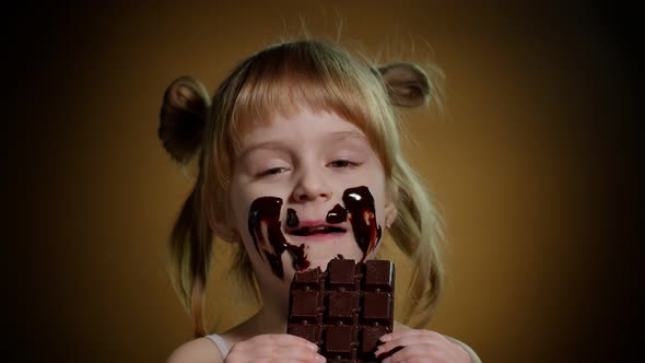 Portrait of Teen Child Kid Smears Face with Melted Dark Chocolate and Starts Eating Chocolate Bar