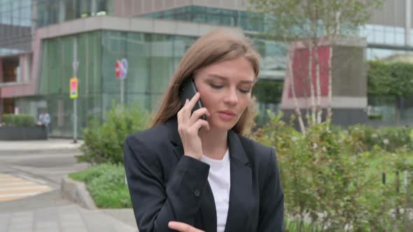 Businesswoman Talking on Phone While Walking on the Street