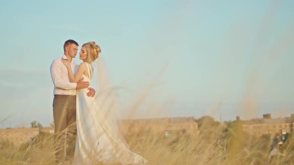 The Wedding Couple Communicates on the Background of the Sky the Bride with a Bouquet of Flowers