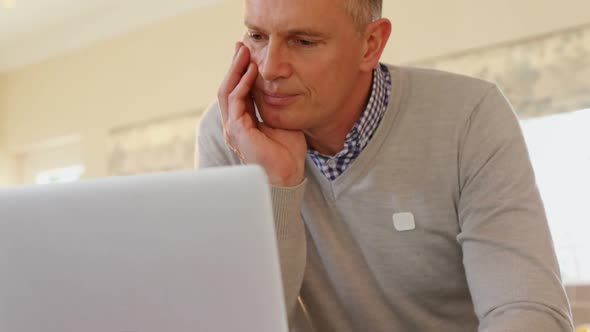 Mature man using laptop in kitchen 