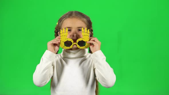 Cute Girl in Funny Glasses Takes Them Off and Shows Their Tongue on Green Screen