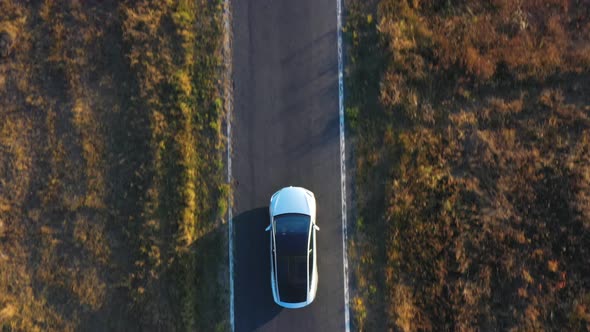 Aerial Shot of Electrical Car Driving on Country Road at Summer Evening