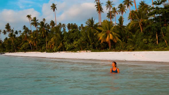 Woman sunbathing in turquoise water white sand beach tropical coastline