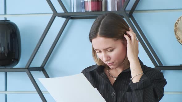 A young brunette business girl stands in the office and looks at documents for a new project