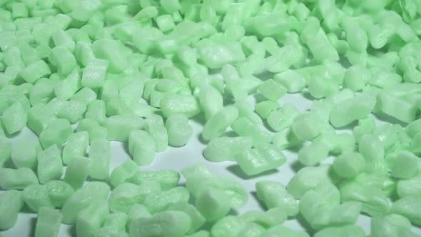 Green Storyfoam Packing peanuts being poured falling into cardboard box, care shipping products 