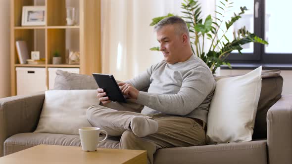 Man with Tablet Pc Sitting on Sofa at Home 