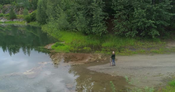 Aerial view of mature woman standing near a lake 4k