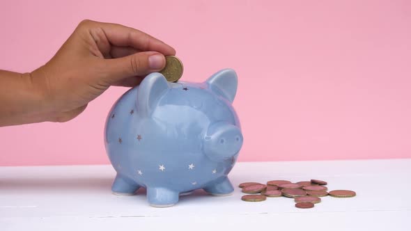 Hand Placing Coin in Piggy Bank