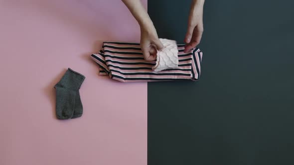 Female Hands Fold Child Clothes on Two Colored Grey Pink Background