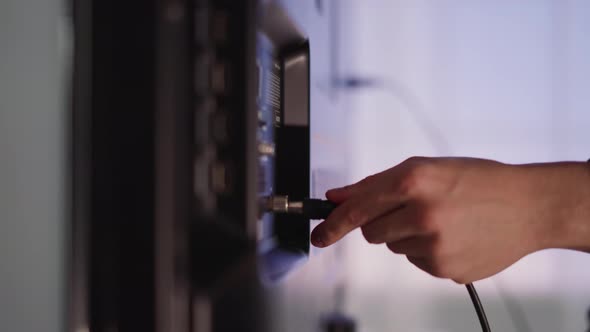 Man Hand Plugs Cable to Smart TV on Blurred Background