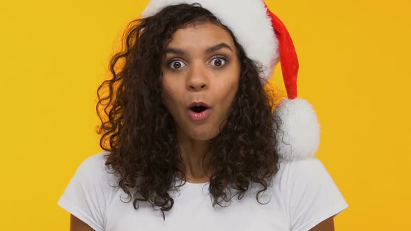 Curly Brunette in Santa Hat Saying Wow, Surprised With Xmas Gift, Festive Mood