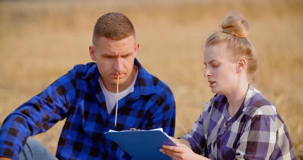 Agriculture - Female and Male Farmers Talking at Wheat Field During Harvesting