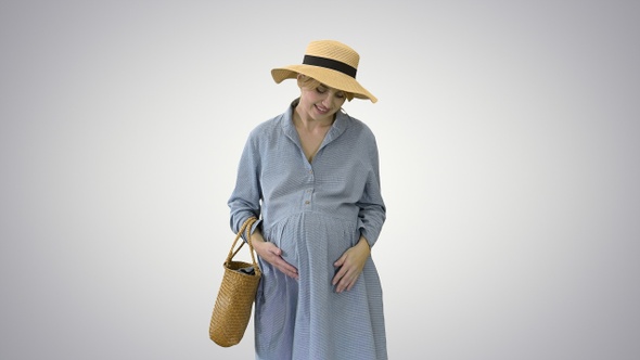 Beautiful pregnant woman in summer clothes with hat touching