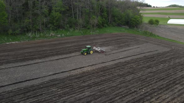 Aerial view of farmer fertilizing and planting the last rows in section of field late in day.