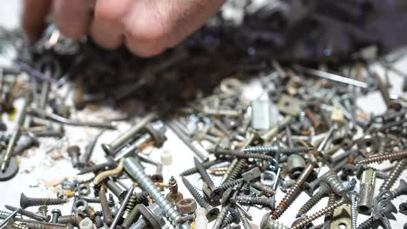 Hand Putting and Sorting Screws Nails Bolts and Washers on the Table