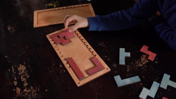 Closeup of Child is Hands Folds a Wooden Logical Toy