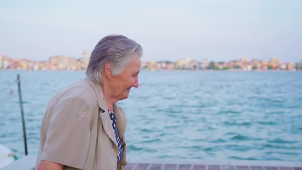 Elderly Lady Traveler Walks on Promenade in Chioggia Smiling