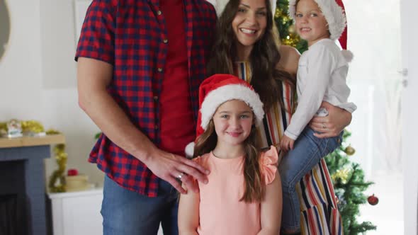 Happy caucasian family wearing santa hats looking at camera