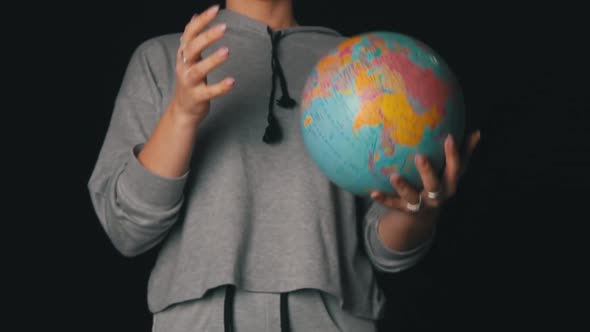 Girl's Hands Toss a Geographic Globe in Slowmo