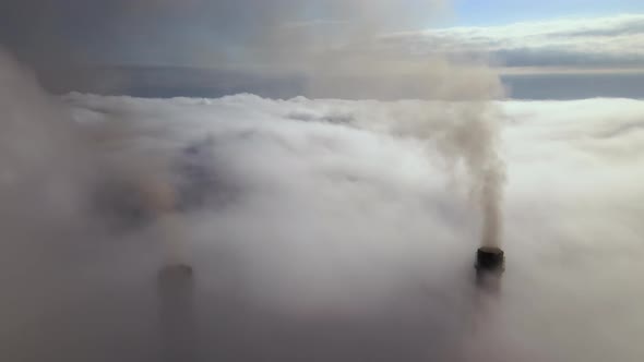 Coal Power Plant High Pipes with Black Smoke Moving Upwards Over Clouds Polluting Atmosphere