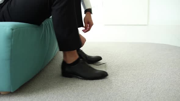 man tying shoelaces on black shoes in the morning