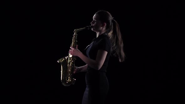 Woman Plays on Saxophone in Slow Motion. Black Studio Background