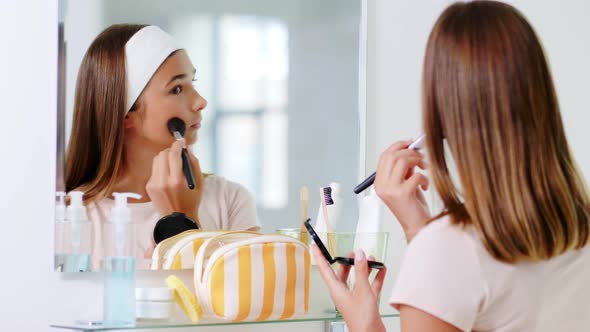 Teenage Girl Applying Powder to Face at Bathroom